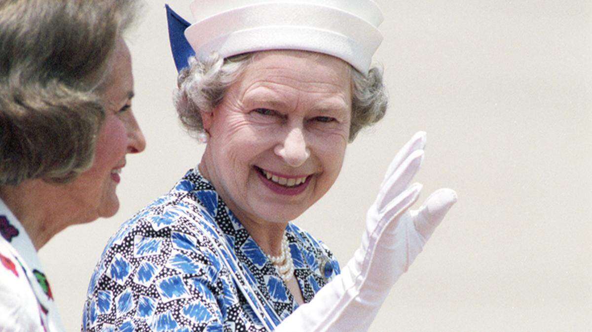 Queen Elizabeth II waves to a crowd of people upon her arrival at Love Field in Dallas with Dallas Mayor Annette Straus on her right.