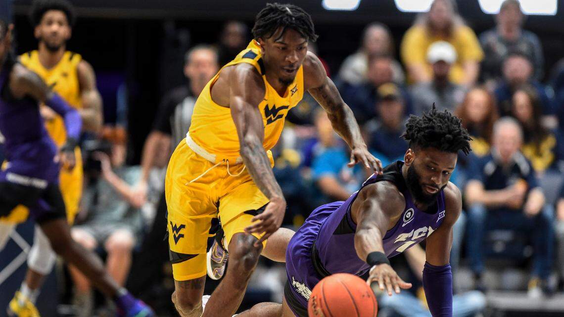 West Virginia guard Kedrian Johnson, left, is called for a foul as he attempts to steal the ball from TCU guard Mike Miles during the first half of an NCAA college basketball game in Morgantown, W.Va., Saturday, March 5, 2022. (AP Photo/William Wotring)