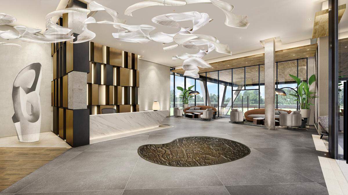 A rendering of the complex's lobby shows modern art work, a granite-counter concierge desk and lounge chairs for guests.