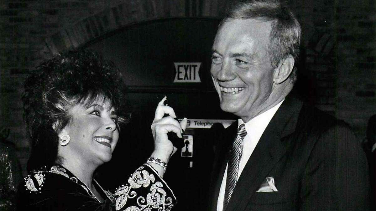 Shot September 25, 1989 - Elizabeth Taylor sprays some of her new men’s cologne - Passion - on Dallas Cowboys owner Jerry Jones at a launching party for the new fragrance held at the Stadium Club at Texas Stadium Monday night. / jjtxm /  (Photo by LESLIE WHITE - staff photographer/The Dallas Morning News)