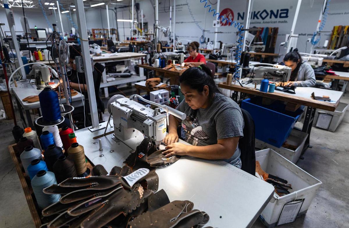 Workers stitch the outer shell of the baseball gloves at their stations in the factory area of the Nokona headquarters in Nocona in June.