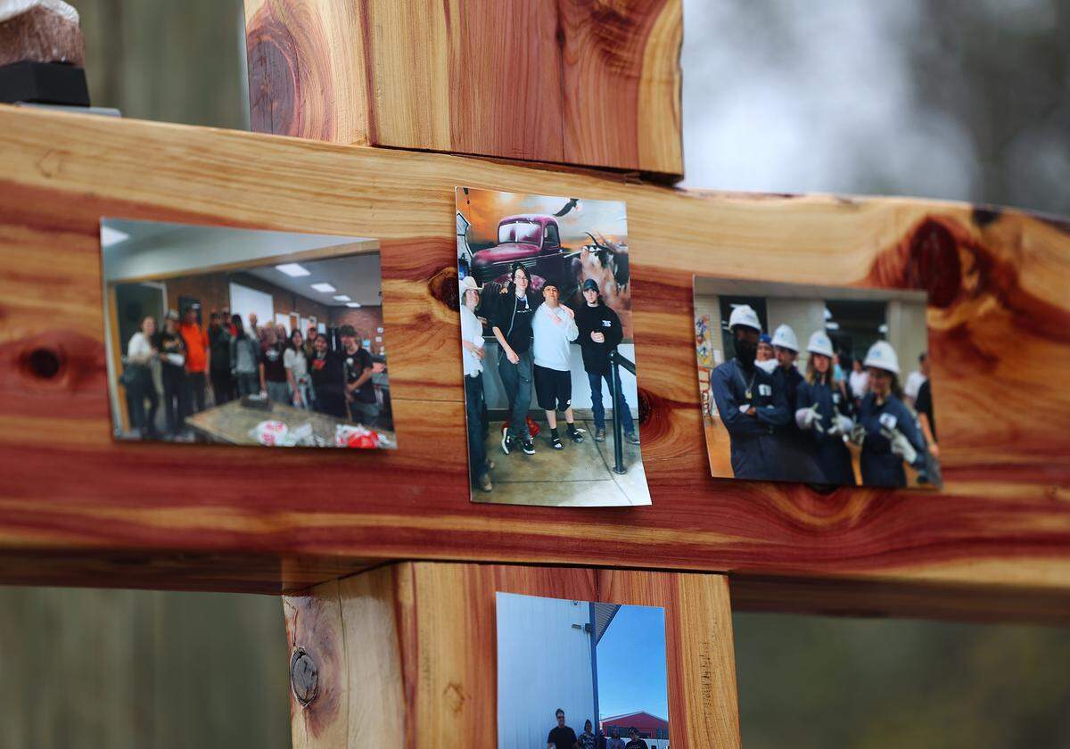 Photographs of Blake Burlock and his church group are taped to a wooden cross marking the area where he was found dead more than a year ago on Northwest 20th Street in Fort Worth.