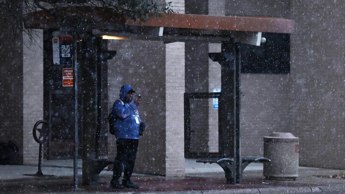 Snow falls as Chris Hall waits at a bus stop on Houston Street in downtown Fort Worth to go home after a night shift on Thursday, Jan. 9, 2025. A winter storm warning is in effect for North Texas.