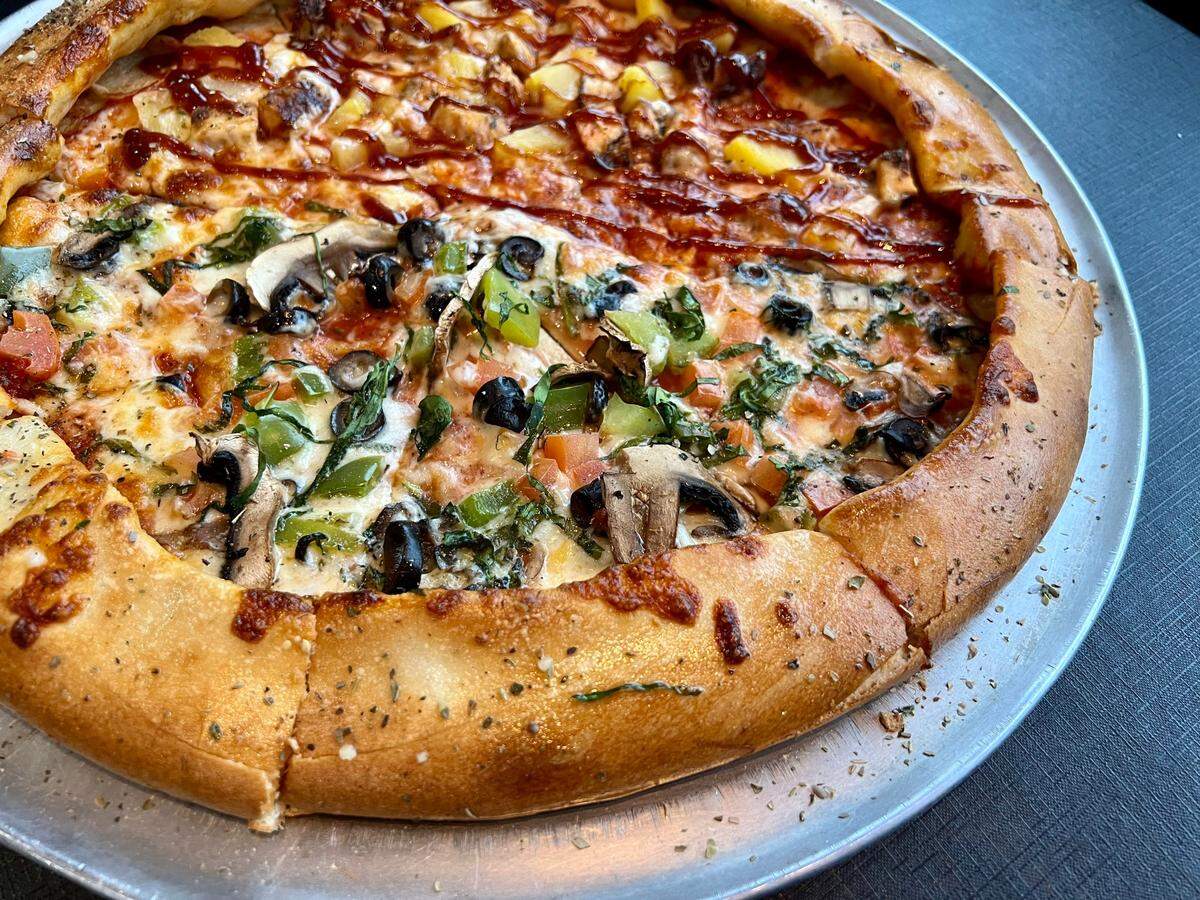 A veggie pizza (foreground) with a half barbecue chicken-pineapple at Sauce’d in Grapevine.