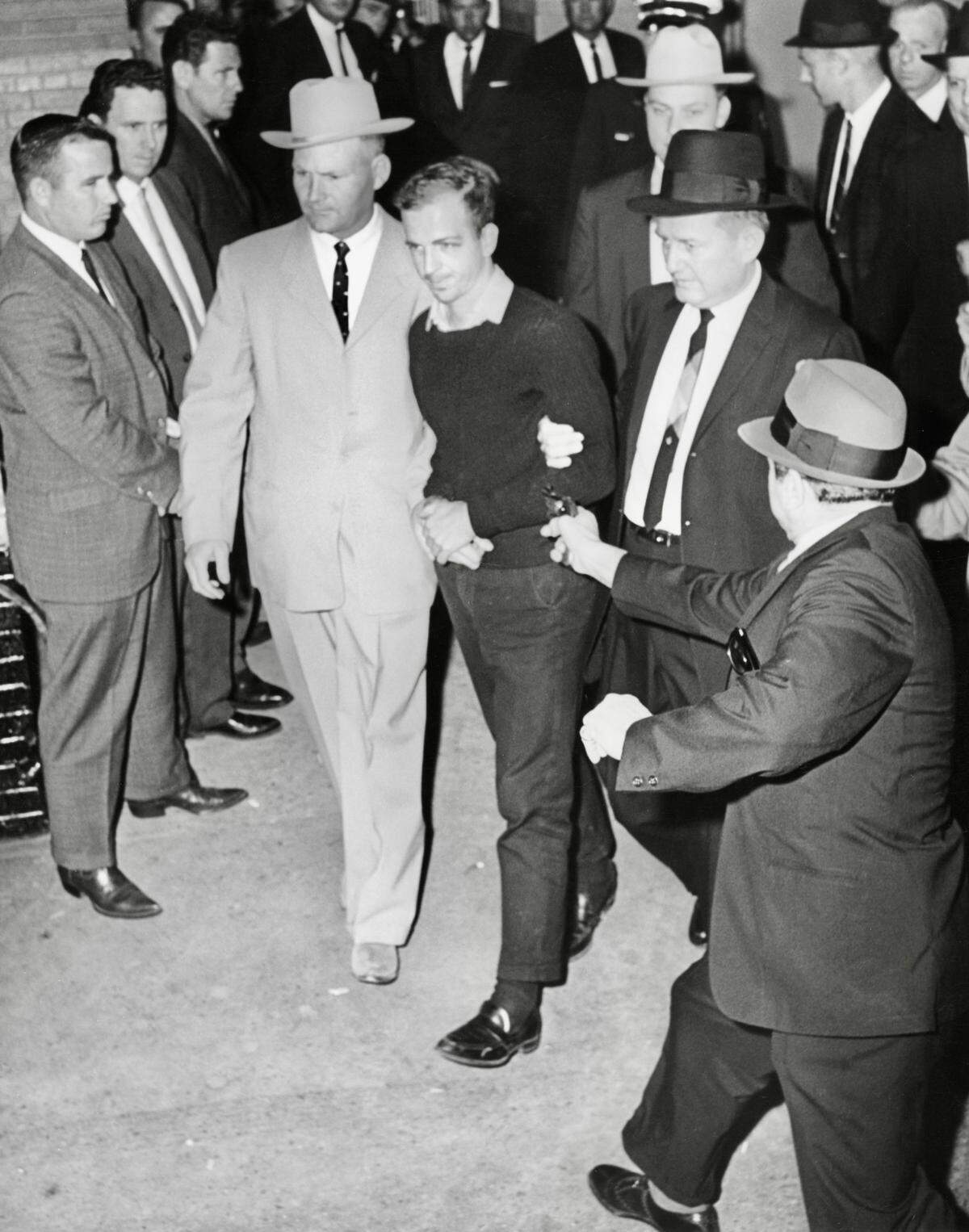 Jack Ruby, foreground, approaches and shoots Lee Harvey Oswald, center in handcuffs, as he is escorted to the Dallas city jail via the underground garage of the Dallas police headquarters, Texas, on Nov. 24, 1963. Oswald is escorted by detectives Jim Leavelle, left, who is handcuffed to Oswald, and L.C. Graves, right. Directly behind Graves is detective L.D. Montgomery.