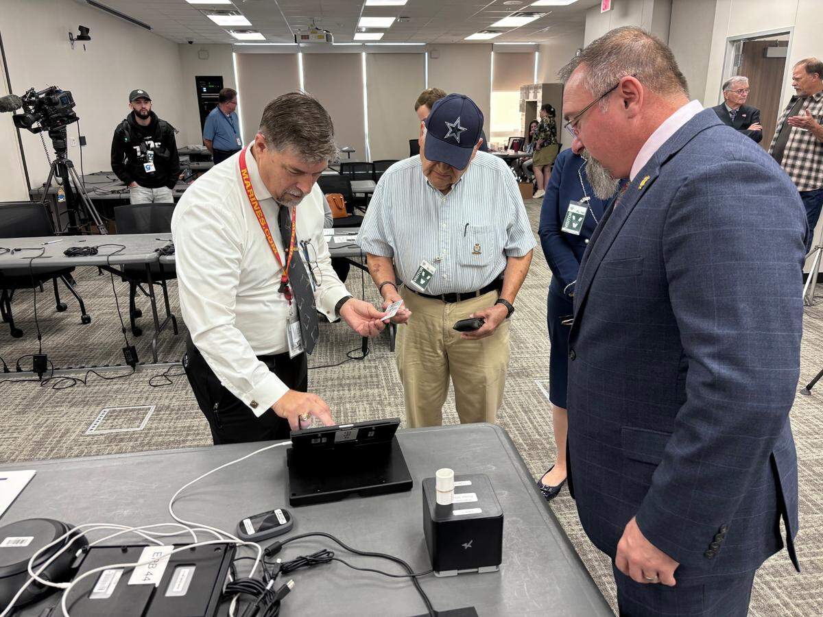 Tarrant County Assistant Elections Administrator Troy Havard assist Ruben Jimenez as he signs in to perform a test of the county’s in-person voting system on Sept. 16, 2024.