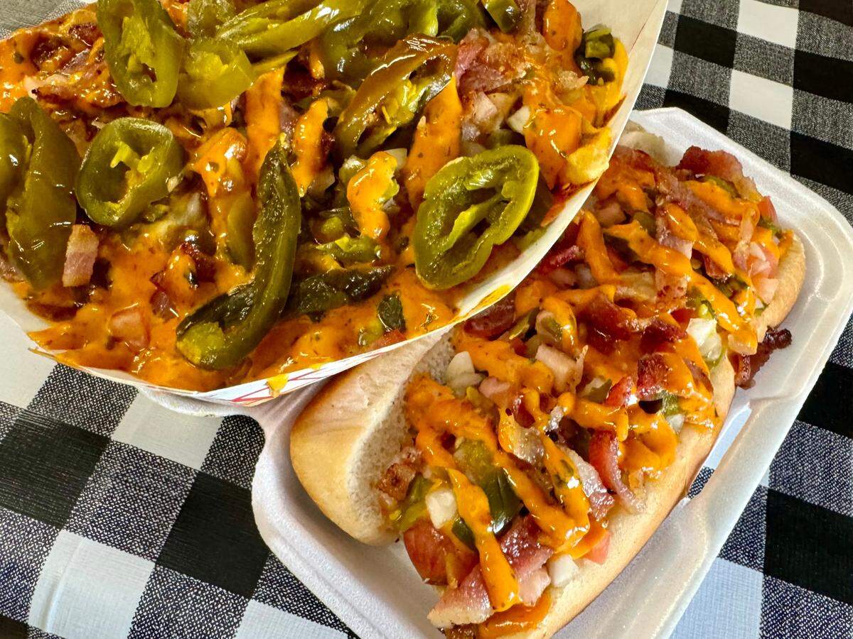 Loaded fries with chili, bacon, jalapenos, cheese and chipotle aioli, and a Nathan’s spicy hot dog with the same toppings, May 21, 2024, at Nearly Famous Burgers & Hot Dogs in Arlington.