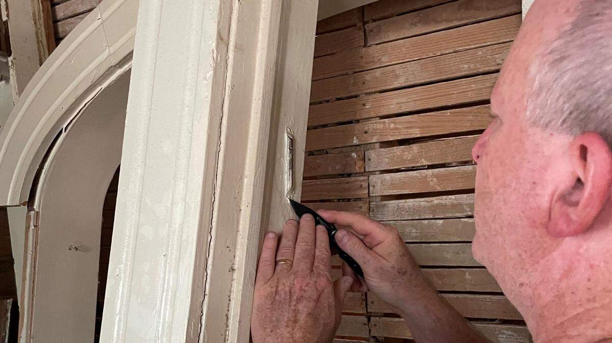 Arthur Moses uses a razor to pry loose a mezuzah, a Jewish religious object, from a door frame from the house that his grandfather owned a century ago.