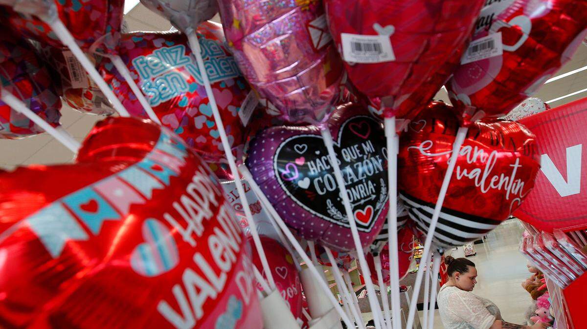 Colorful Valentine’s Day balloons are seen in the foreground as a woman picks some stuffed animal gifts at Walgreen’s in New Bedford, Mass., on Monday.