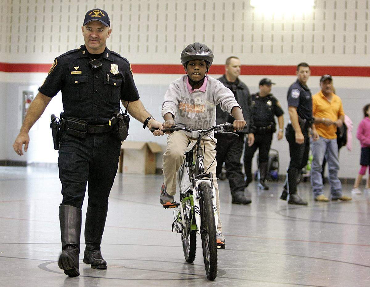 In this 2015 photo, Neil Noakes, a Fort Worth police sergeant at the time, escorts Jayce Smith, 10, across the gym with his new bicycle at Sydney Poynter Elementary School.