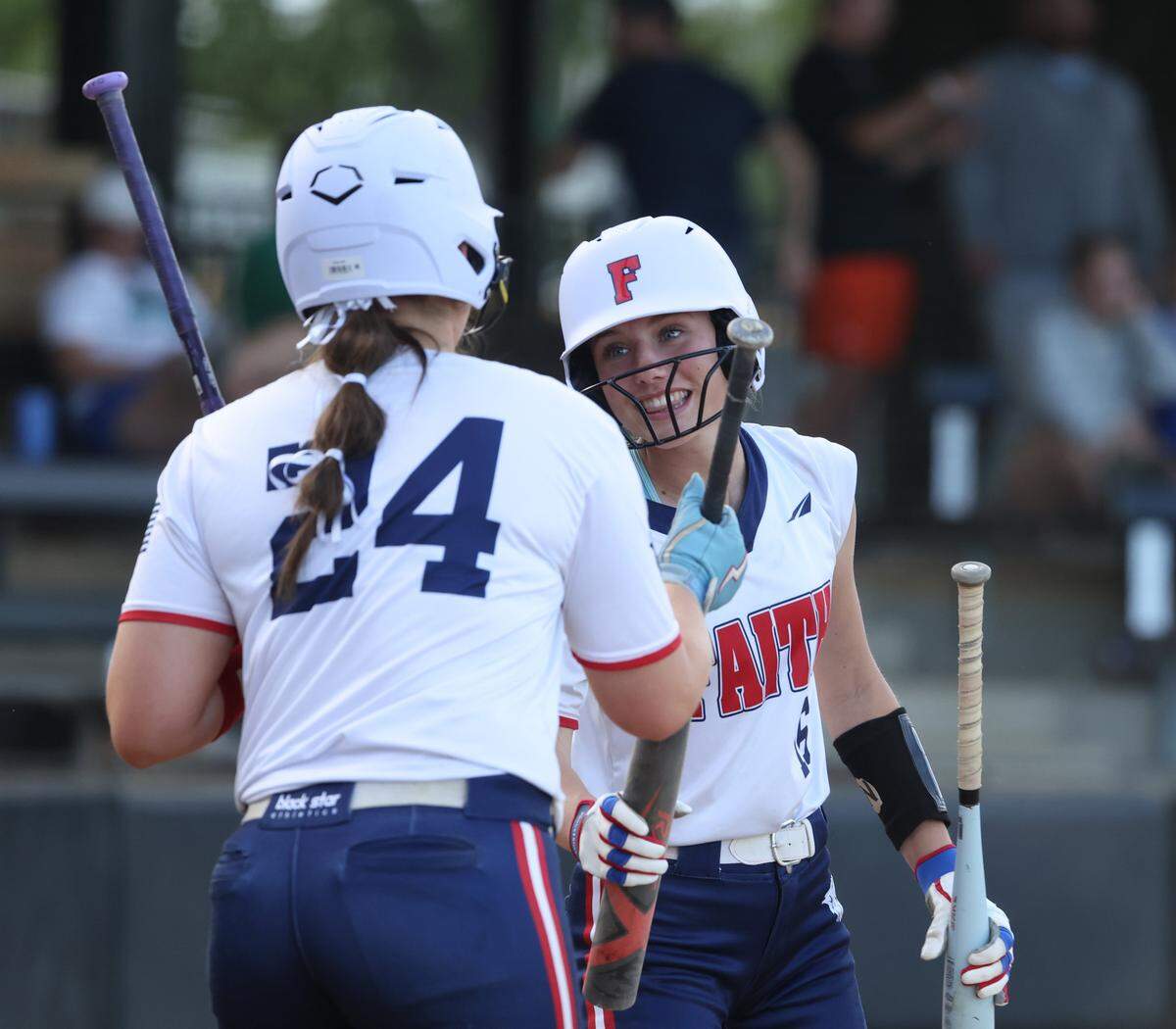 Grapevine Faith center fielder Michaela Hamilton hands a bat to Jocelyn Monroe during a softball game at Oak Grove Park in Grapevine, Tx. Tuesday, March 31, 2026