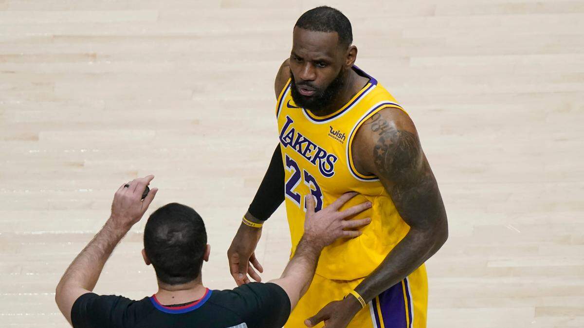 LeBron James is restrained by an official as he reacts to a fan in the second half of a game against the Atlanta Hawks Monday night. The woman was ejected from the arena. James later referred to her as “Courtside Karen,” which trended on social media.