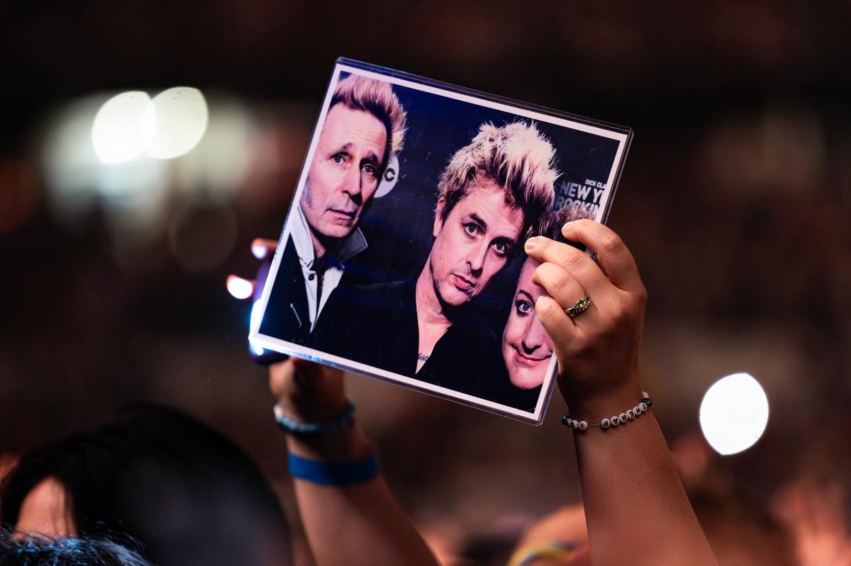A fan waves a picture of Mike Dirnt, Billie Joe Armstrong and Tré Cool from Green Day during “The Saviors Tour” at Globe Life Field in Arlington on Wednesday, Sept. 11, 2024.