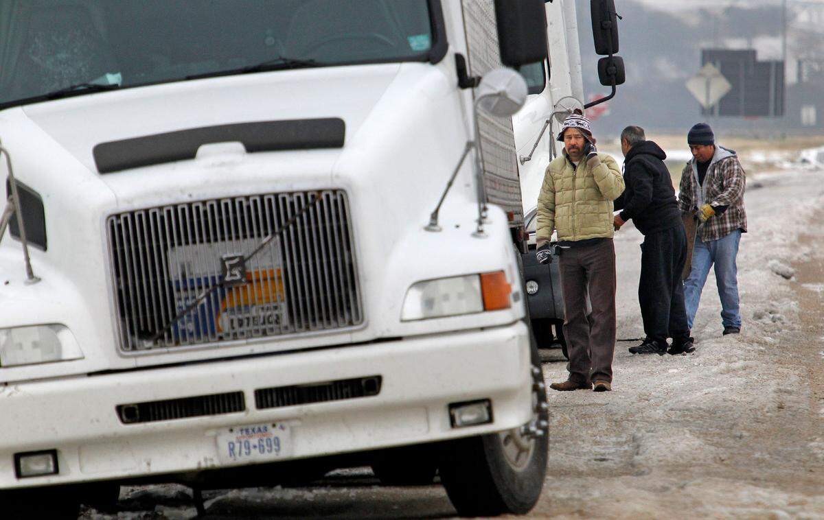 Truckers Alonso Medina (on cell, left) and Santos Ortiz (far right) tried to help another driver (center, refused ID) whose semi was stranded on the shoulder of I-20 (westbound) near Winscott in Benbrook. Two of the drivers were headed to Celifornia, one to Lubbock. Cold and ice remained in Fort Worth Sunday, with roads especially treacherous in the the morning hours before temperatures rose, Sunday, December 8, 2013. (Star-Telegram/Paul Moseley)