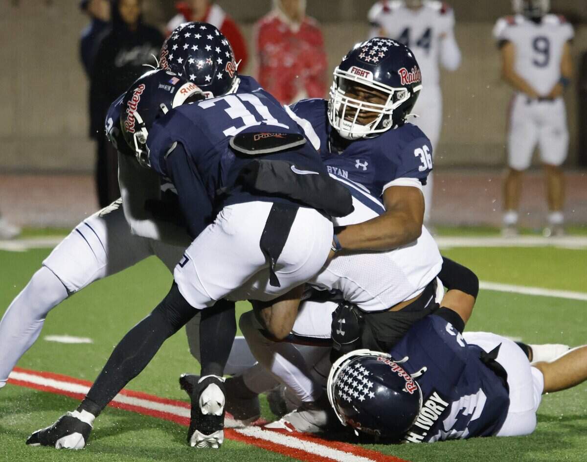 Richland wide receiver Ben Sanders (10) is smothered by the Raider defense including Denton Ryan defensive back Alijah Friday (31), defensive lineman Christian Ivory (33) and linebackers Sadik Bassirou (36) and Roy Mongo (26) during the second half of a UIL Class 5A Division I Regional on Friday Nov. 28, 2025 at Buddy Echols Field in Coppell, Texas.