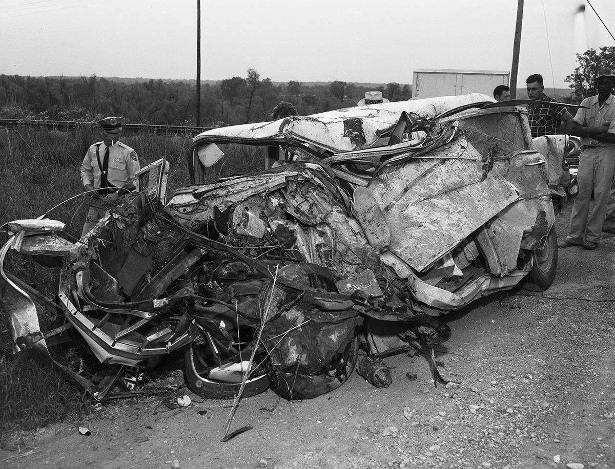 May 13, 1958: Highway Patrolman Howard L. Robuck of Grapevine and curious bystanders examine the car in which Sidney A. Morse of Denton was riding when it rammed a freight train. Morse was killed as the car was knocked down embankment into a telephone pole.