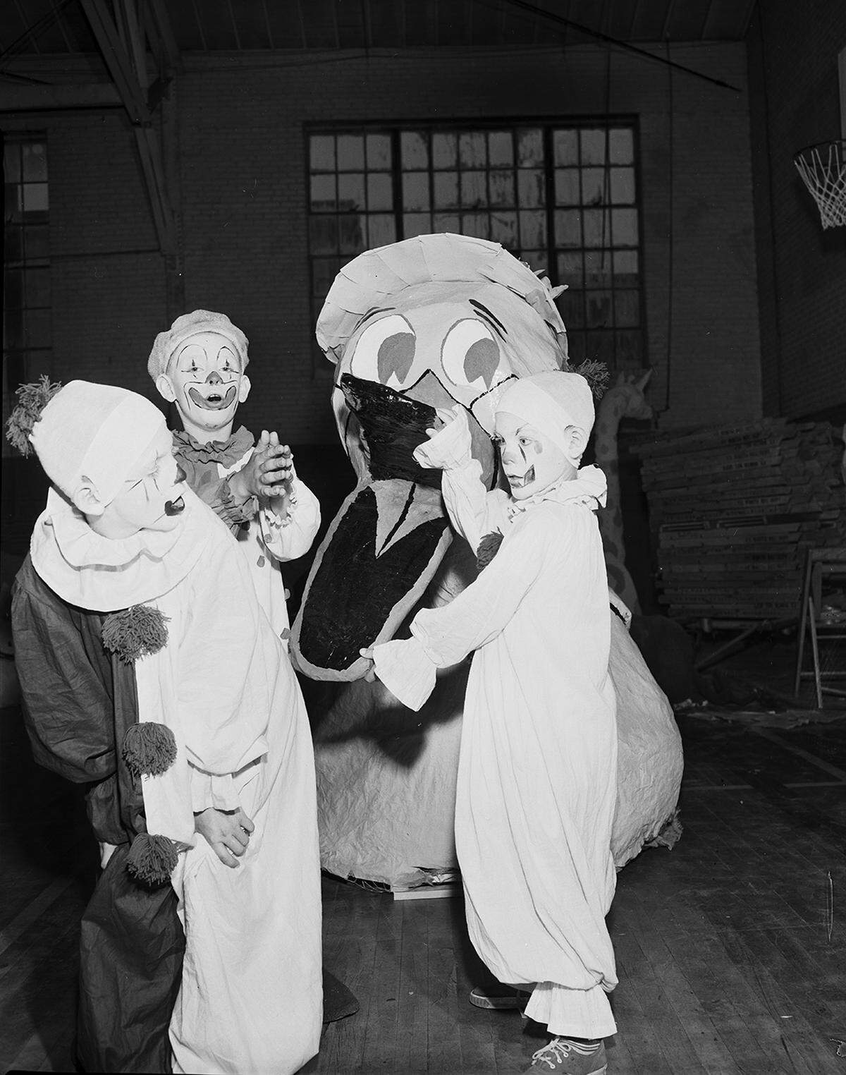 Three children dressed as clowns pose for a photo making faces.