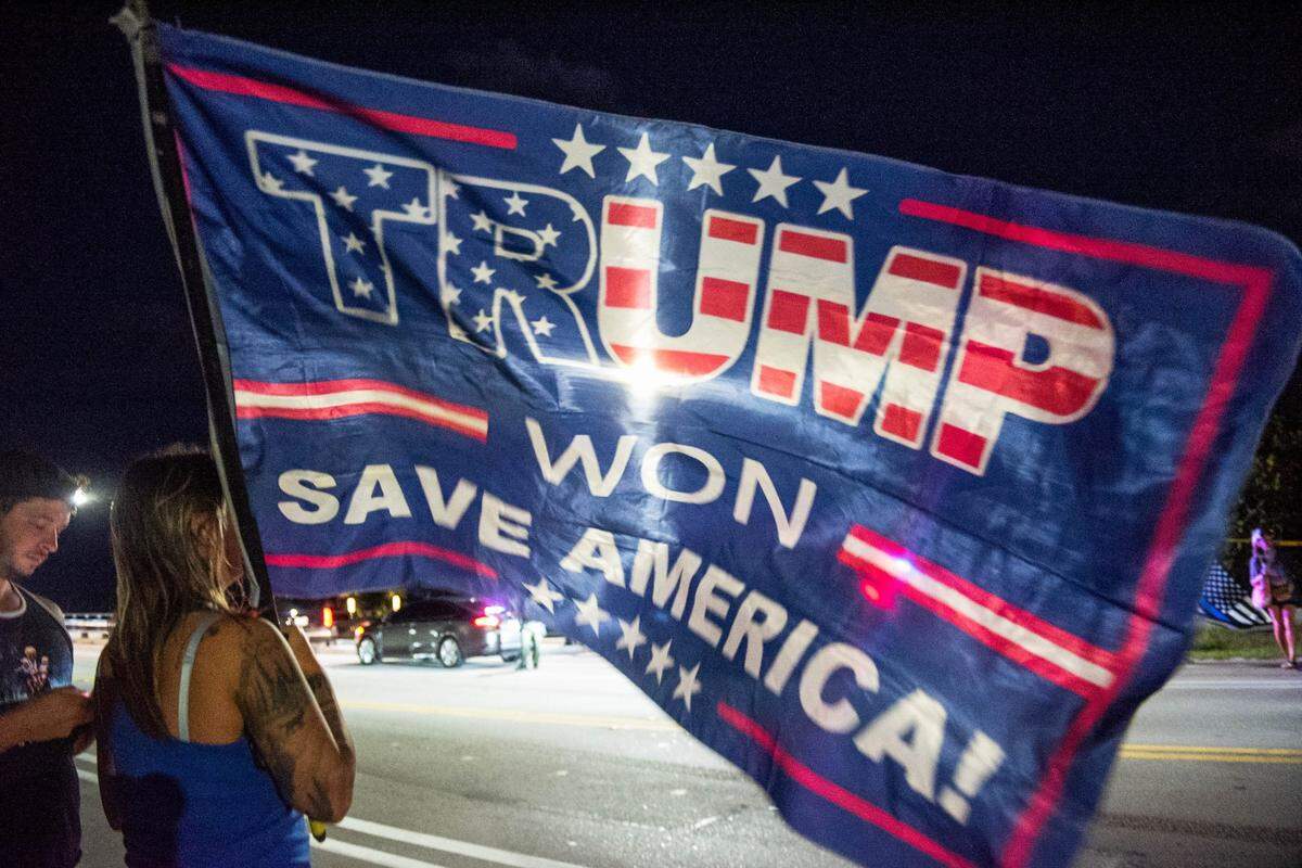 Lydia Hanson of West Palm Beach, Florida, holds a Trump flag near Mar-A-Lago, former President Donald Trump’s residence, in March. Trump convinced his voters that Democrats used tools such as mail ballots to steal the 2020 election.