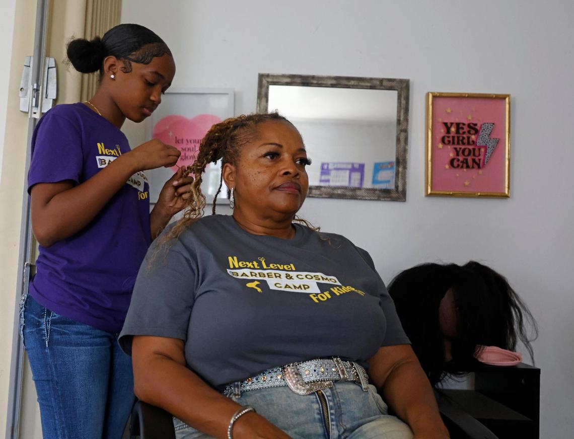 Serenity Brown, 11, works on the hair of assistant director Patrice Carroll at Next Level Barber and Cosmo camp.