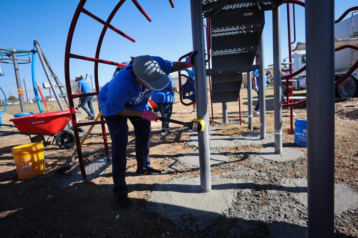 Sonji Patmon, volunteer, cleans cement from around playground equipment the group installed Nov. 16, 2021, at Worth Heights Elementary in Fort Worth.