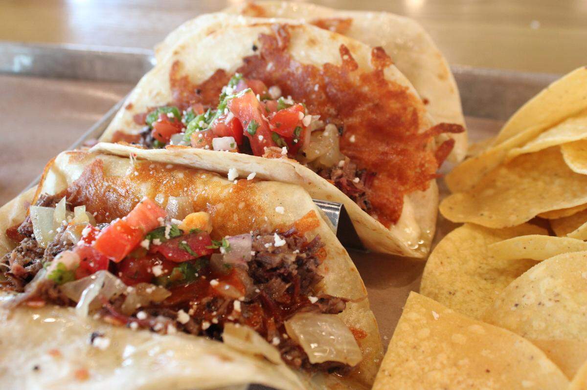 Loop 9 brisket tacos served with a side of chips and housemade salsa.
