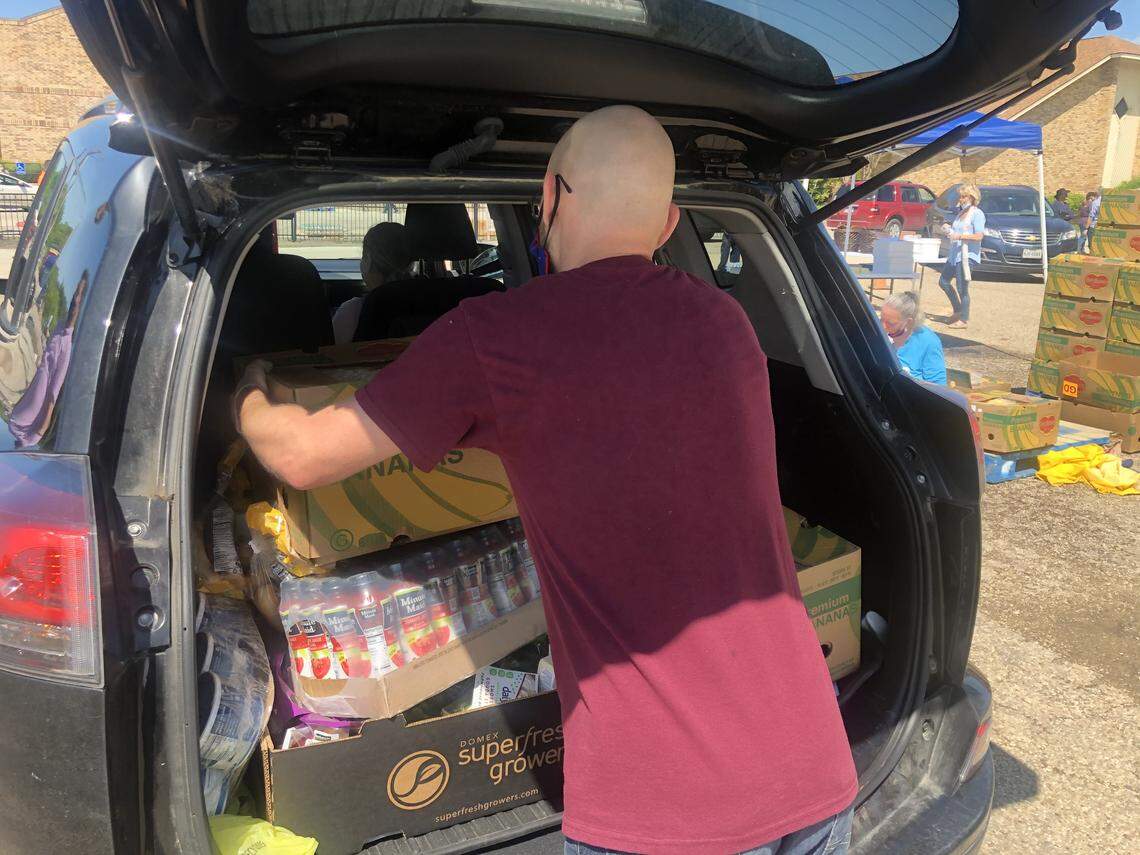 Lance Burke, 22 of Burleson, loads bananas into the back of a car during an event at OpenDoor Church that saw an estimated 2,000 cars loaded up with fresh produce for Easter.