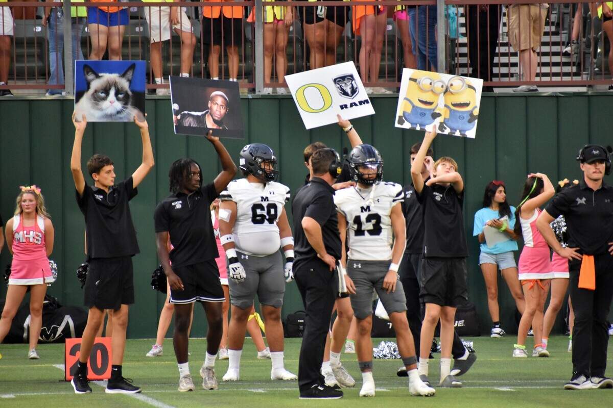 Arlington Martin quarterback Chase Devoll, right, prepares to head out onto the field to start a play drive while teammates hold up signs for the play call against Arlington Lamar in a UIL Class 6A football game at Choctaw Stadium in Arlington on Thursday, Sept. 18, 2025.