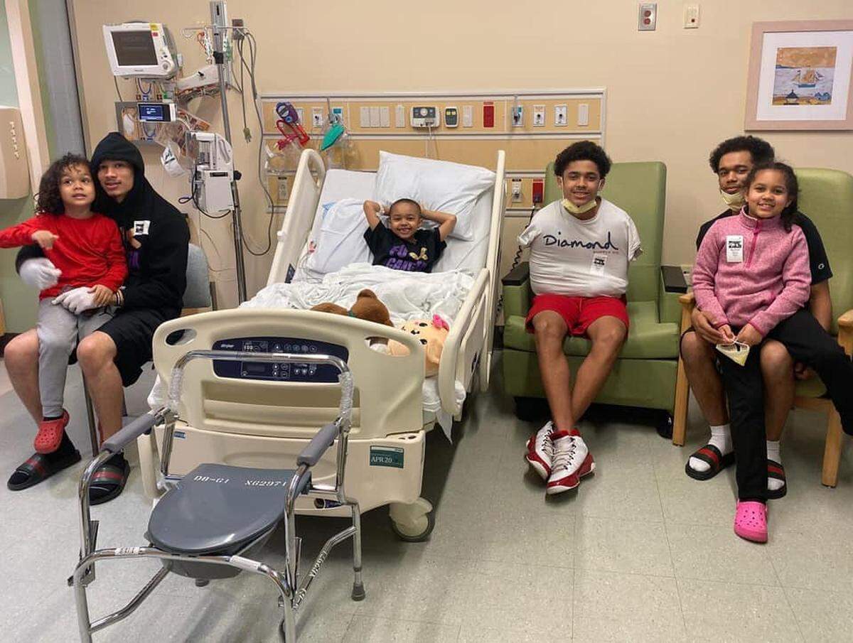 Adriana Nixon (center) lies in a hospital bed, surrounded by her family, after receiving her new liver. She and her older sister, Alana Nixon (far right), had spent the past weeks playing games and attending a virtual summer camp.