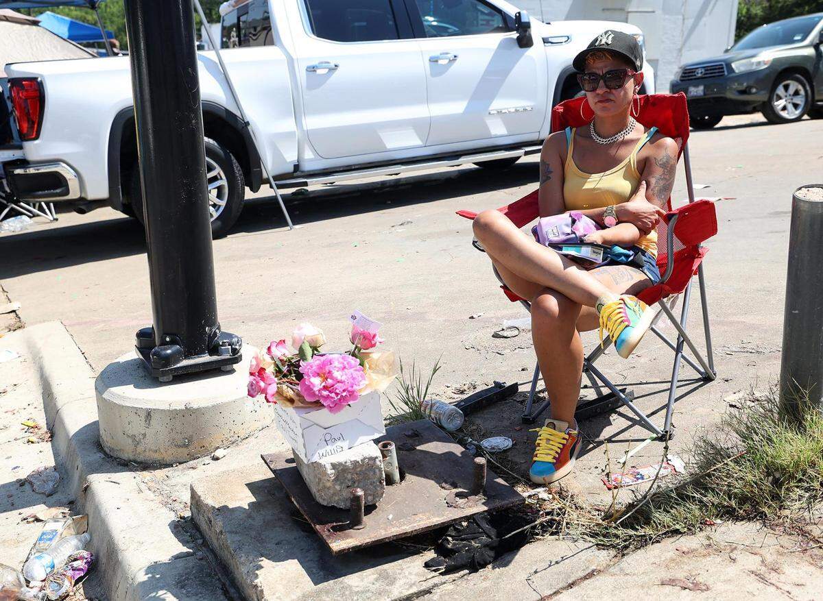Ka’Desha Weatherly sits in the spot where her son, Paul Timothy Willis, 18, was killed in a shooting during a Fourth of July celebration the previous evening. Weatherly had flowers with her son’s name on them sitting in front of her as the Fourth of July parade traveled down Horne Street in the Como neighborhood on Tuesday, July 4, 2023.