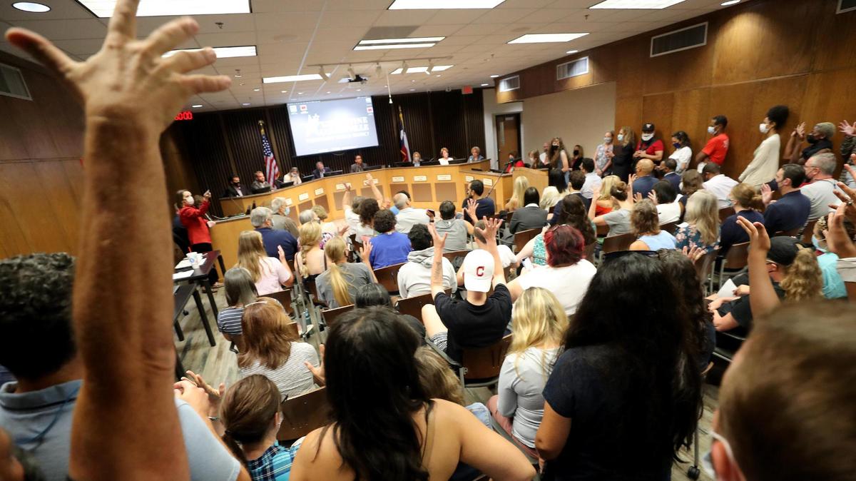 People in the crowd raise their hands to silently applaud a supporter of James Whitfield speaking at a Grapevine-Colleyville school board meeting on Monday, September 20, 2021.