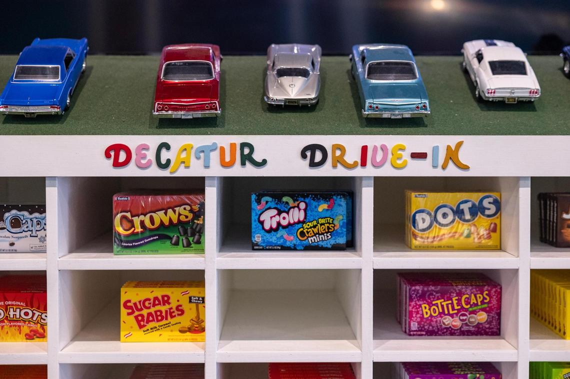 A shelf with various candy brands is labeled the ‘Decatur Drive-In’ with retro toy cars on top of it at Hey Sugar Candy Store in Decatur on Thursday, March 29, 2025.