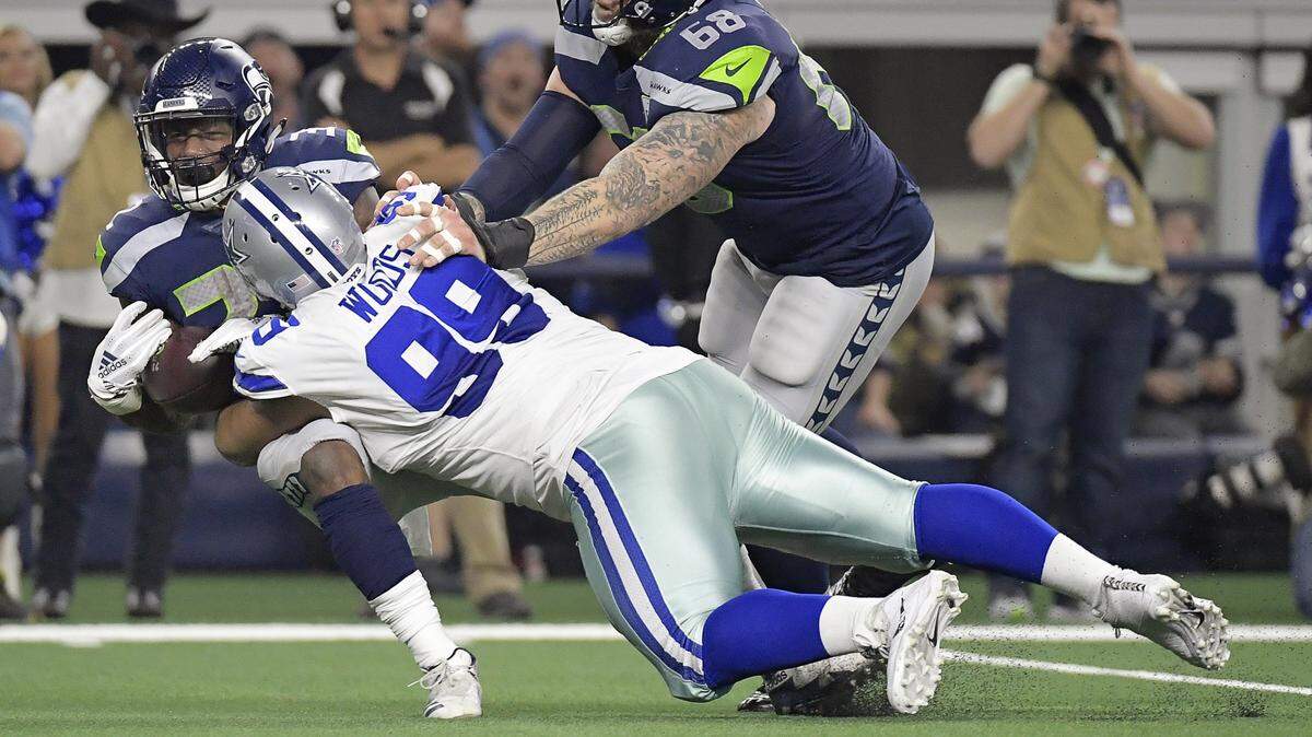 Dallas Cowboys defensive tackle Antwaun Woods (99) takes down Seattle Seahawks running back Chris Carson (32) while center Justin Britt (68) can’t make the block as the Cowboys beat the Seahawks 24 to 22 in a NFL Wild Card playoff game at AT&T Stadium in Arlington, TX, Saturday, Jan. 5, 2019.