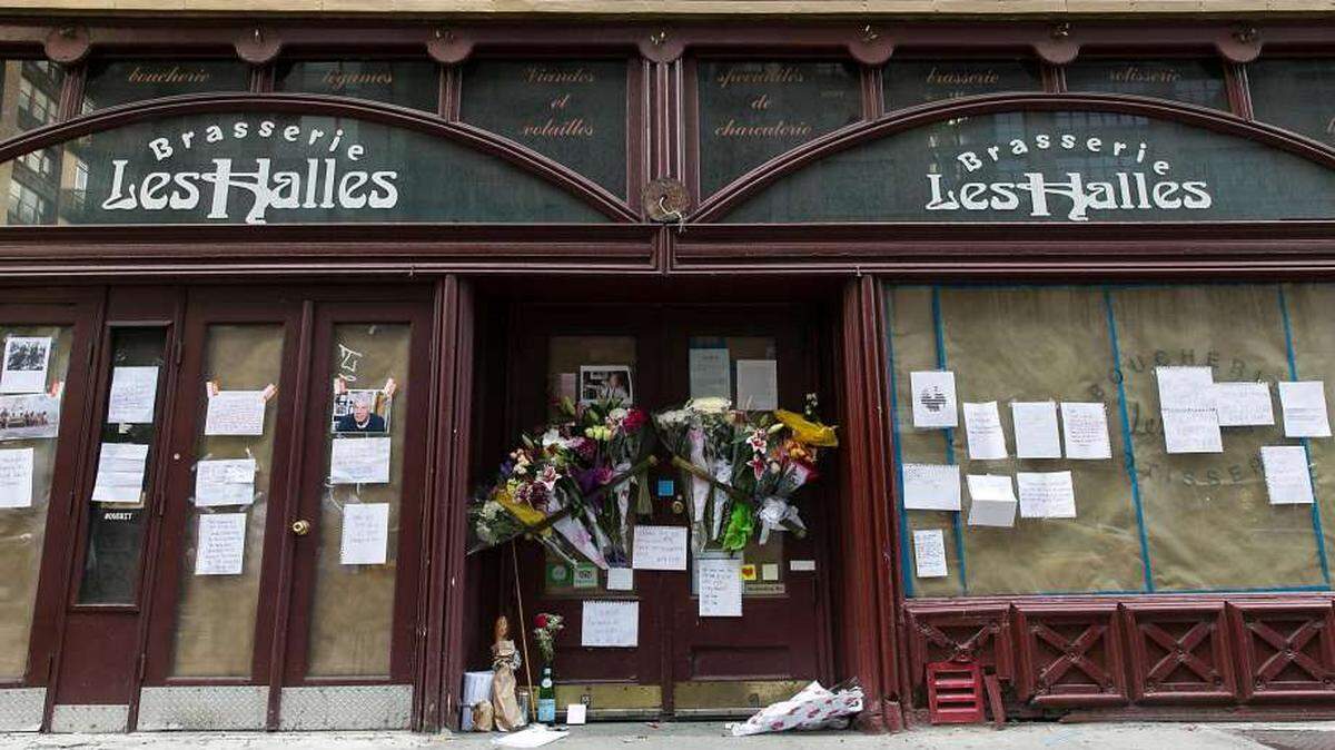 French baguette, a chef toque, cigarettes, and a red rose in a Pellegrino bottle at the memorial for the late celebrity chef Anthony Bourdain in front of his former New York restaurant, Brasserie Les Halles, at 411 Park Ave South, in Manhattan, on June 8, 2018.