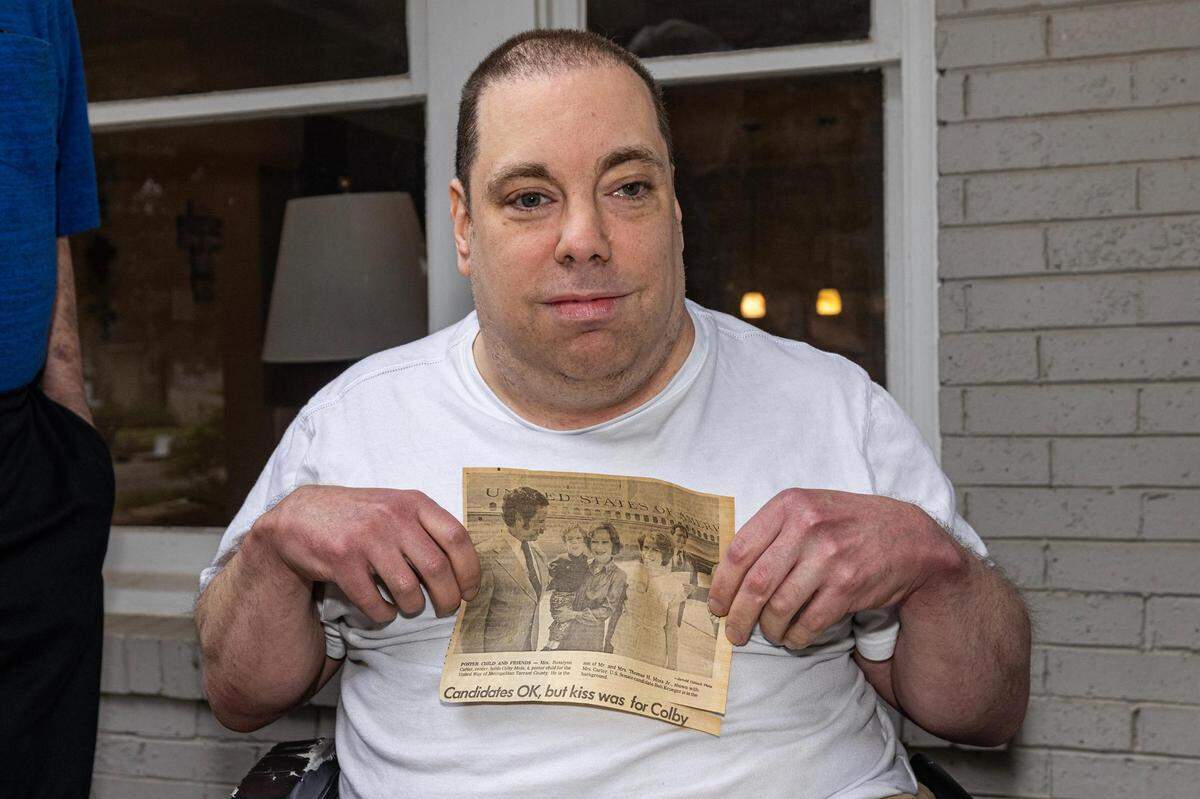 Colby Moss holds up a newspaper photo of himself when he met former First Lady Rosalyn Carter when he was 4.