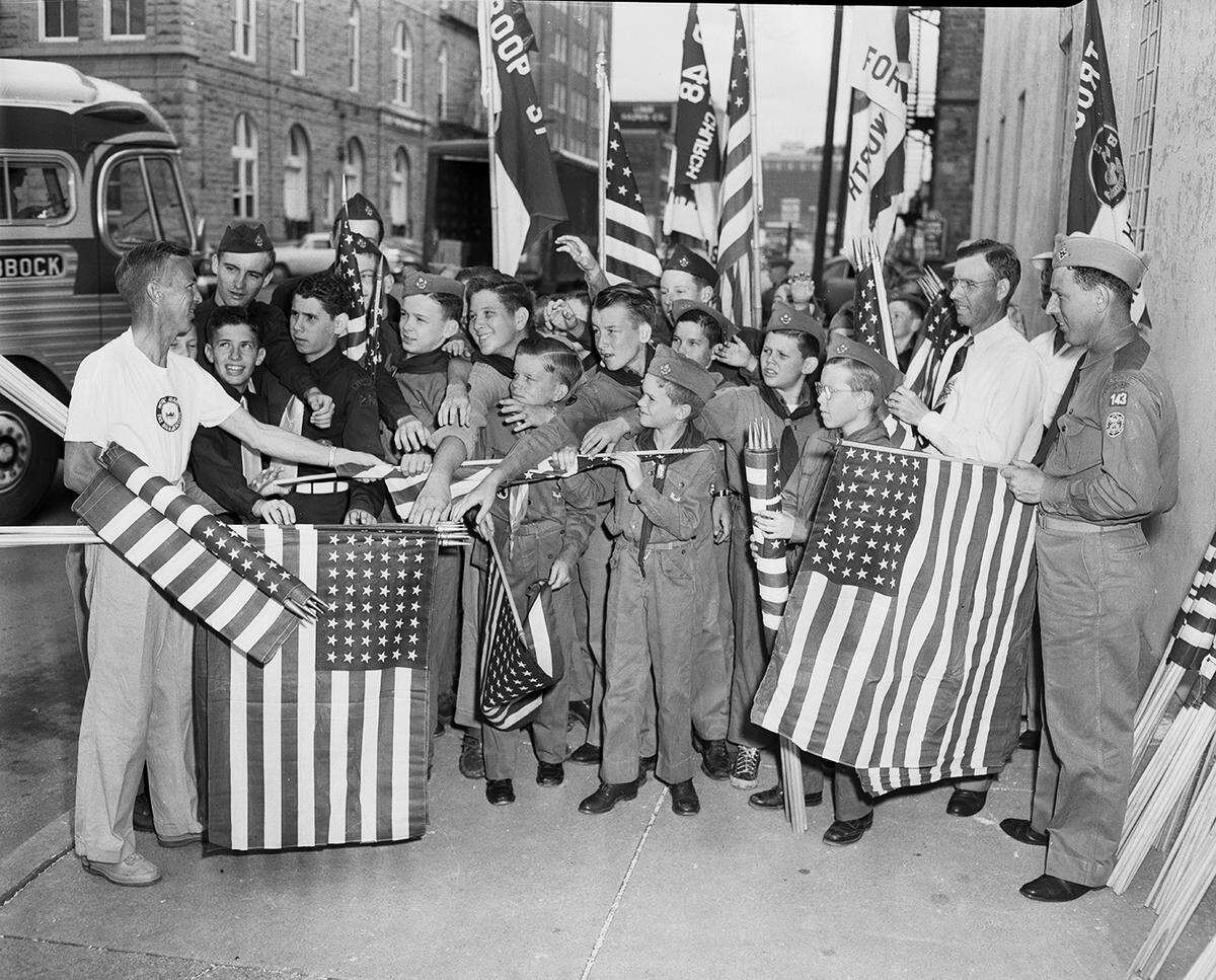 June 16, 1951: The National Guard Armory on E. Lancaster was a distribution point for dozens of U.S. flags with which Boy Scouts and Sea Scouts lined Lancaster for Gen. Douglas MacArthur’s entrance into the city. Handing them out is Art Miller, left, Horned Frog Boy Scout district commissioner, assisted by Scoutmaster Joe Waggoner, in uniform at right, and Buck Rosenthal, assistant scoutmaster, at Waggoner’s right.