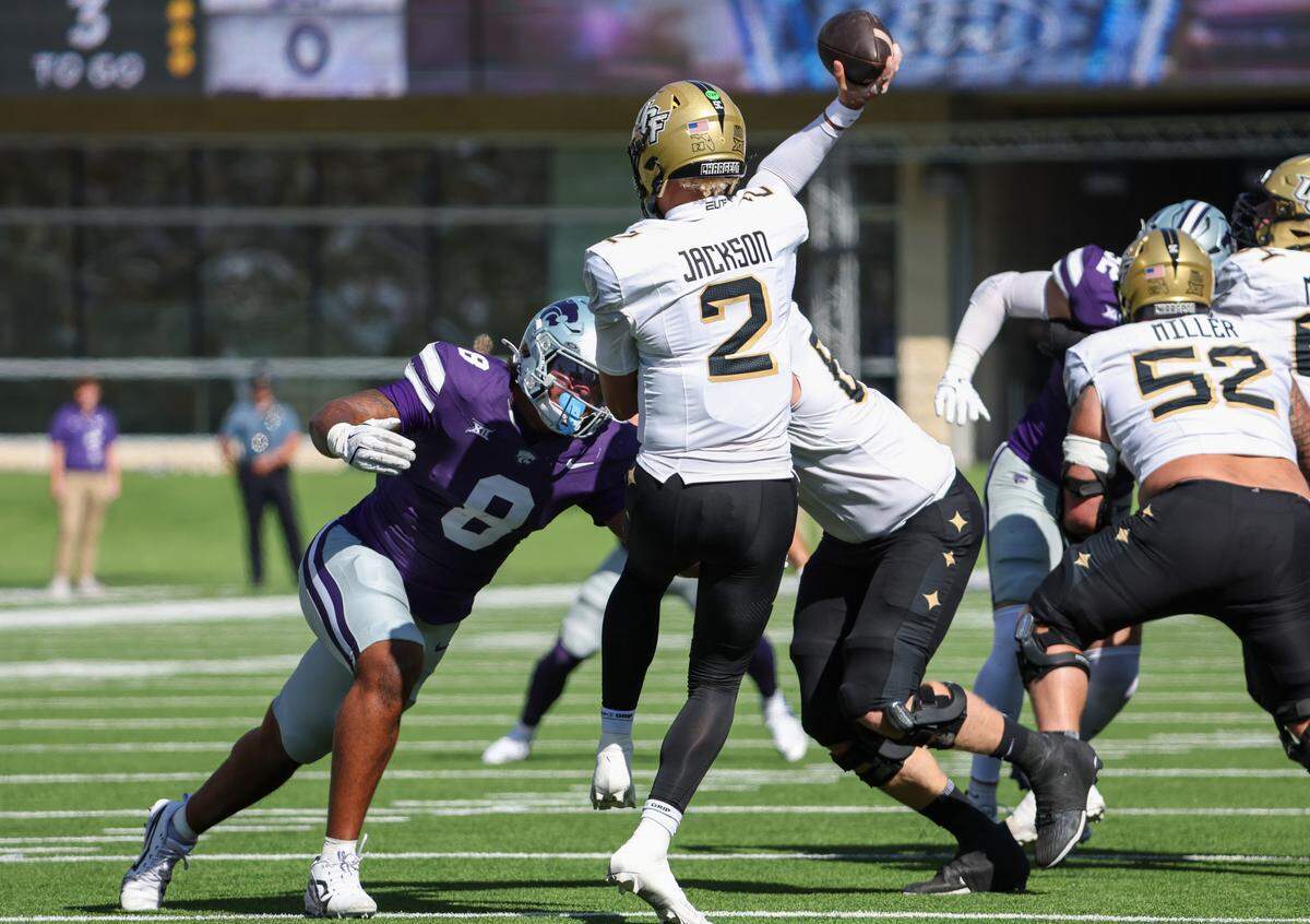 Sep 27, 2025; Manhattan, Kansas, USA; UCF Knights quarterback Tayven Jackson (2) is hit by Kansas State Wildcats defensive end Chiddi Obiazor (8) as he passes the ball during the first quarter at Bill Snyder Family Football Stadium. Mandatory Credit: Scott Sewell-Imagn Images