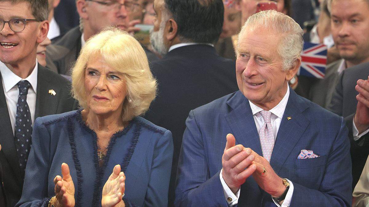 King Charles III and Camilla Queen Consort standing side-by-side clapping.
