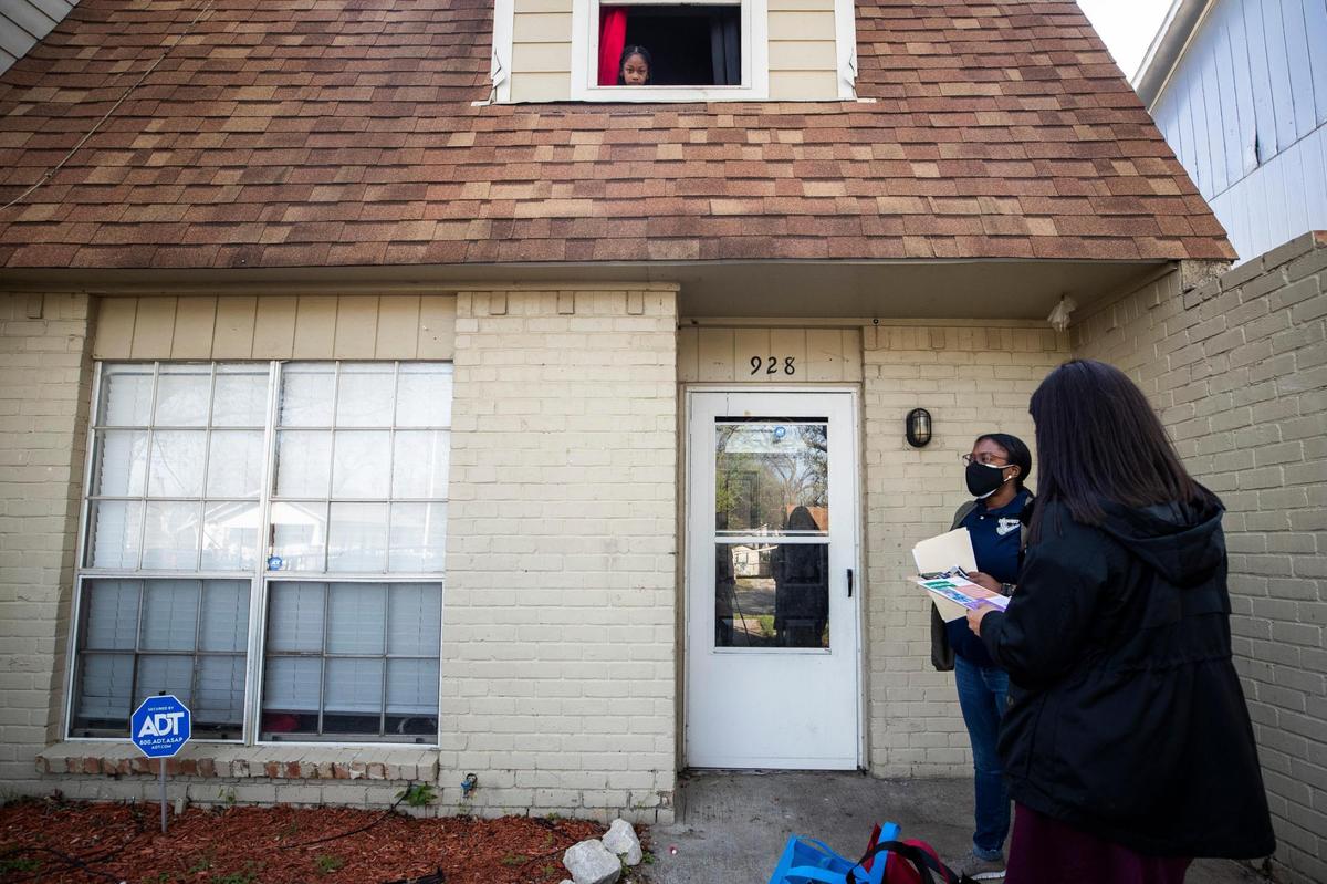 Tahiry Green, 6, peeks out the window as LaShun Cabness, a family and community partnership manager at Oakhurst Elementary School, and Anabel Montes, a service coordinator with MHMR Tarrant County, wait at the front door Wednesday, March 24, 2021, in Fort Worth. MHMR and Fort Worth ISD teamed up to do visits in an effort to reach students who are disengaged from school during the pandemic.