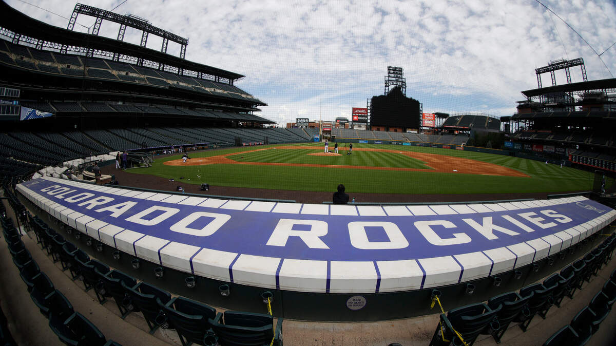 As seen through a fisheye lens, cloud dapple the sky over Coors Field as Colorado Rockies starting pitcher Chi Chi Gonzalez warms up on the mound as the team practices Saturday, July 4, 2020, in Denver. (AP Photo/David Zalubowski)
