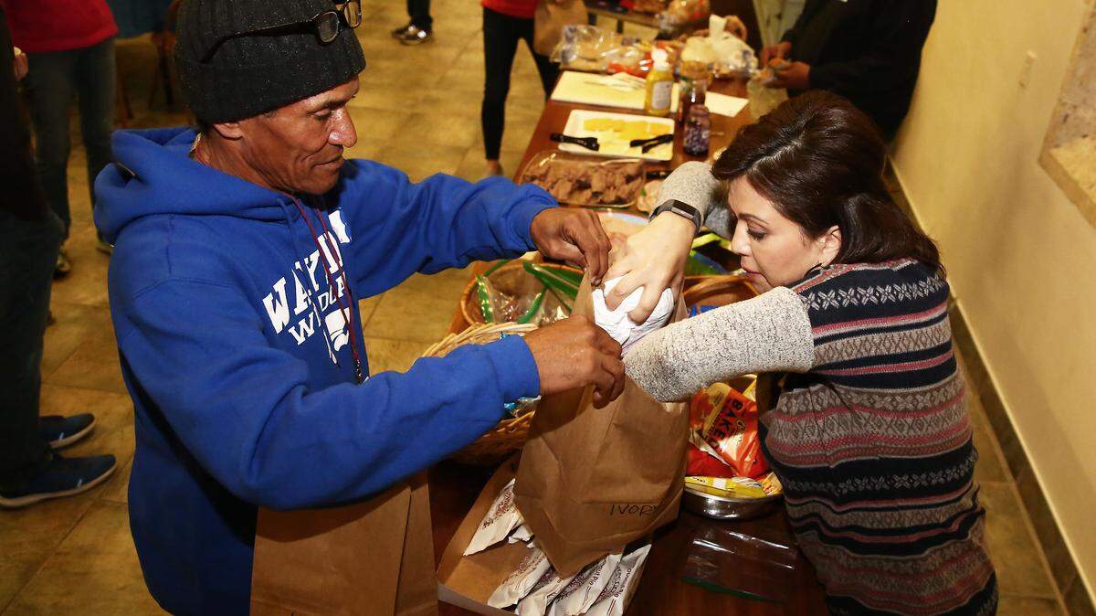 Mary Witt, a shelter volunteer, helps overnight guest Ivory Bynum with a care bag, which includes a guest choice of cookies, pies, candy bars, cheese, crackers, sandwiches and more.