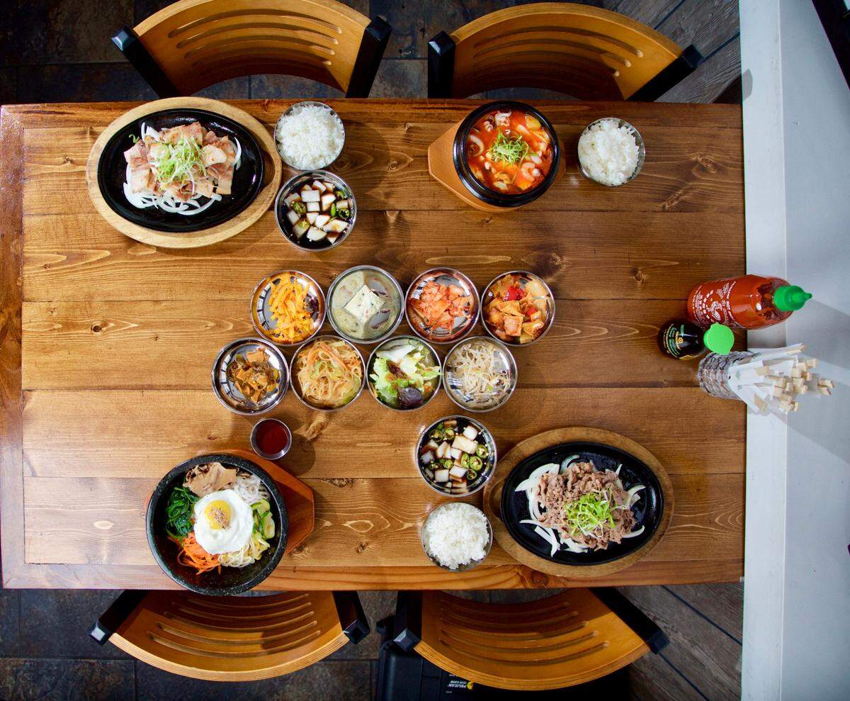 Main entrees clockwise from top left, pork belly, seafood stew, beef bulgogi, dolsot bibimbap and assorted side dishes at Hoya Korean Kitchen in Fort Worth October 12, 2017.