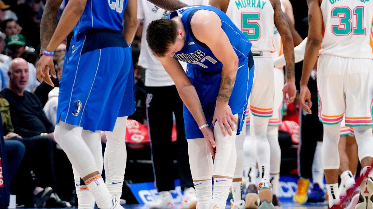 Luka Doncic reaches for his leg after suffering an injury Sunday.