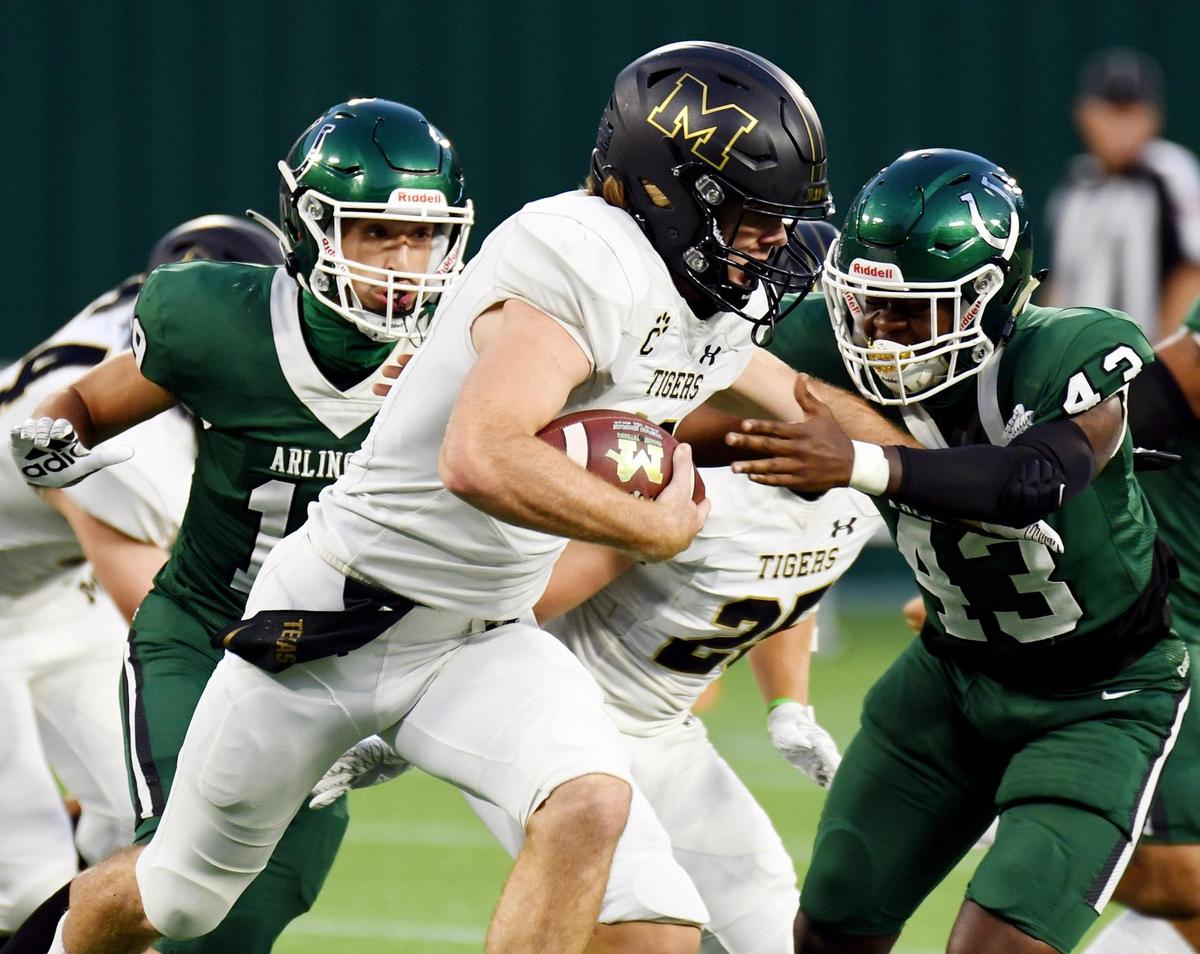 Mansfield quarterback, Hunt Young, center stiff arms Arlington’s SirMichael Brice as he takes the football out of the backfield in the first quarter of their football game Friday, September 25, 2020 at Globe Life Park in Arlington, Texas. Special/Bob Haynes