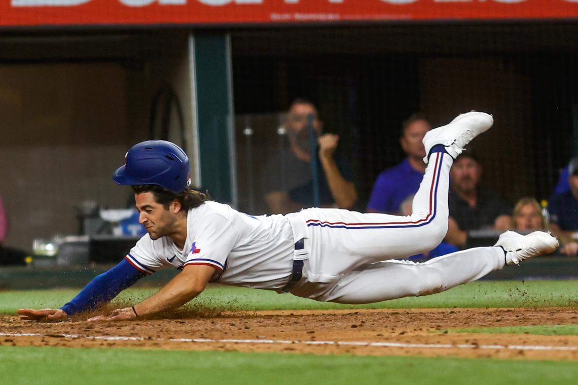 Rangers shortstop Josh Smith slides into home plate on March 30, 2023, at Globe Life Field in Arlington. The Texas Rangers beat the Philadelphia Phillies 11-7.