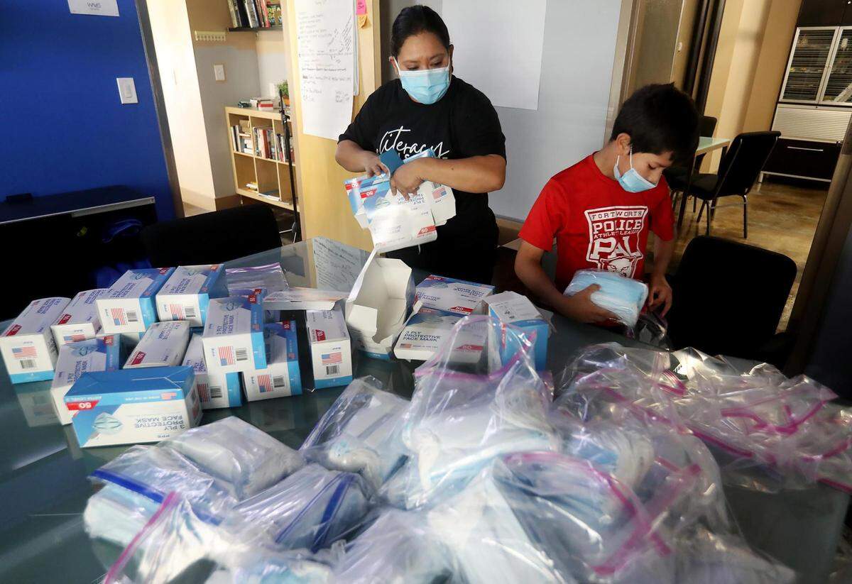 Roxanne Martinez and her son, Jayson Valdez, 9, assemble personal protective kits for residents of their Diamond Hill neighborhood in March 2021. Martinez, who is critical of vaccination efforts by Tarrant County and the UNT Health Science Center, helped organize assistance for her community throughout the pandemic.