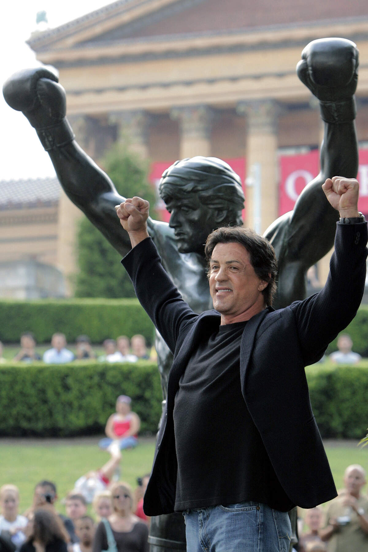 FILE - In this Sept. 8, 2006, file photo, actor Sylvester Stallone poses in front of the bronze statue of Stallone portraying the boxer Rocky Balboa after it was unveiled near the steps of the Philadelphia Museum of Art in Philadelphia, rear. (AP Photo/George Widman, File)
