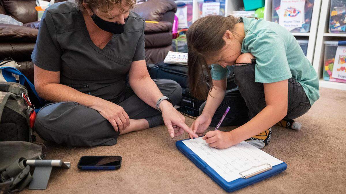Frida Piñón works on her penmanship with Cody McGrew, occupational therapy assistant, at her home in Crowley. Frida and her brother and sister each have cerebral palsy and need special education services along with English-learning services.