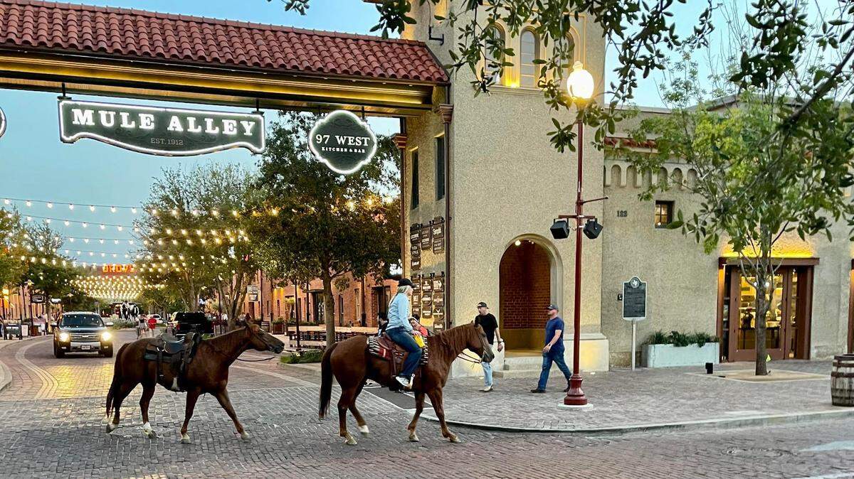 A pair of horses pass the entrance to Mule Alley in the Fort Worth Stockyards on Sept. 8, 2022.