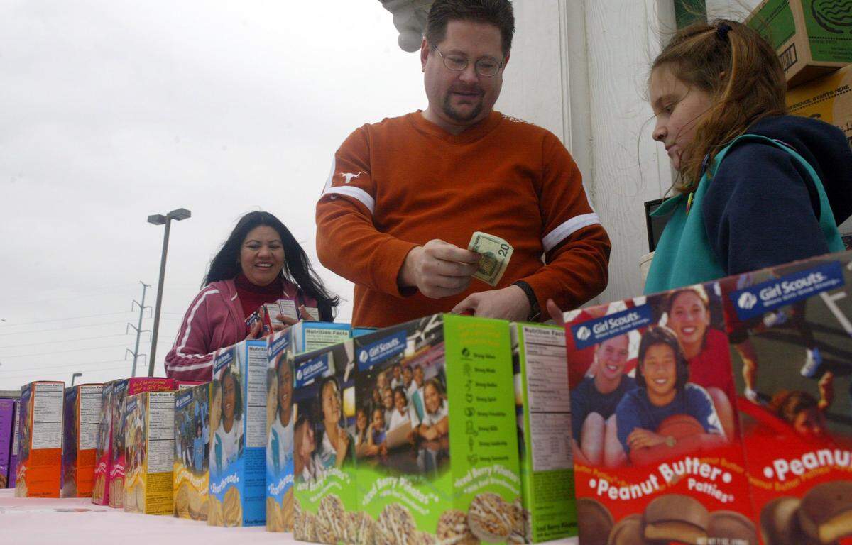 Feb. 19, 2005: Antonieta Walker holds three boxes of cookies as Scott Walker pays Kendall McGahey, 11, for them outside the Ol’ South Pancake House in Fort Worth. The girls are asking customers if they would like to purchase a box to be sent of to the troops fighting in Iraq.