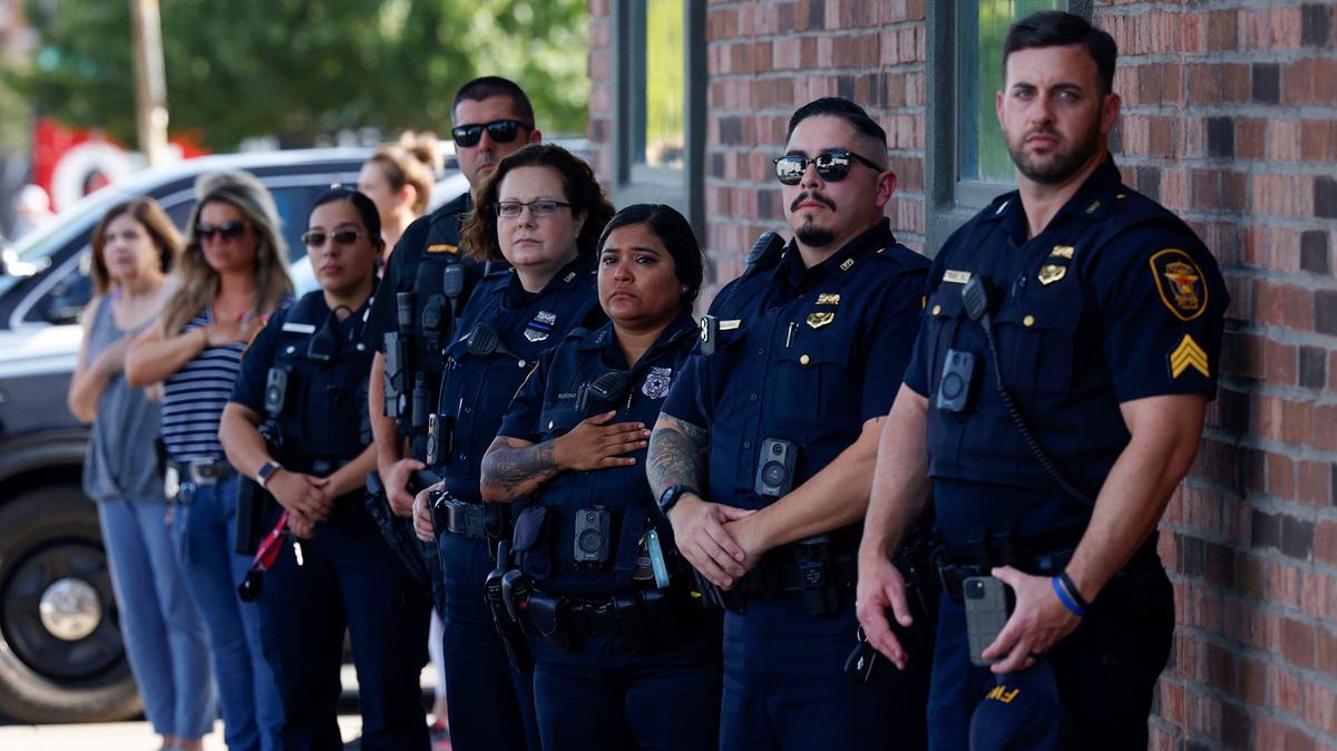 Fort Worth Police Department officers watch the procession for fallen Fort Worth police Sgt. Billy Randolph from outside their station on Magnolia Street on Saturday, Aug. 17, 2024.